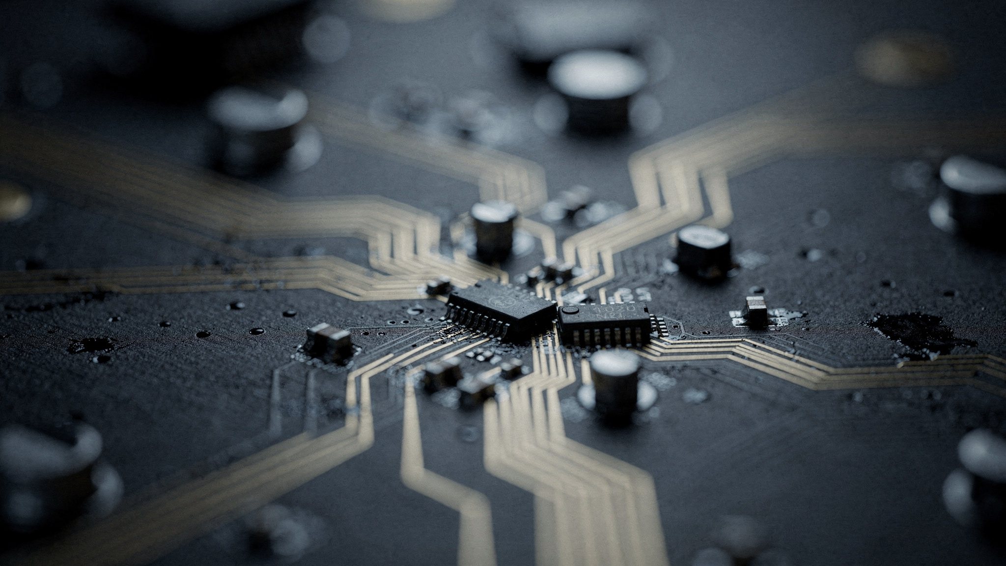 Extreme close-up of a circuit board, gold traces and capacitors on a black surface